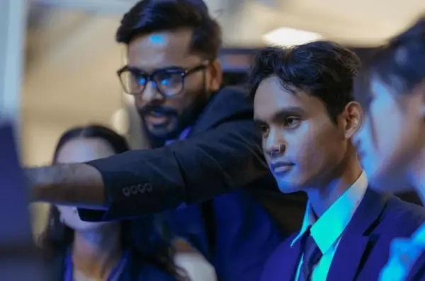 Business professionals collaborating during a corporate meeting while reviewing data on a digital screen in a modern office environment.